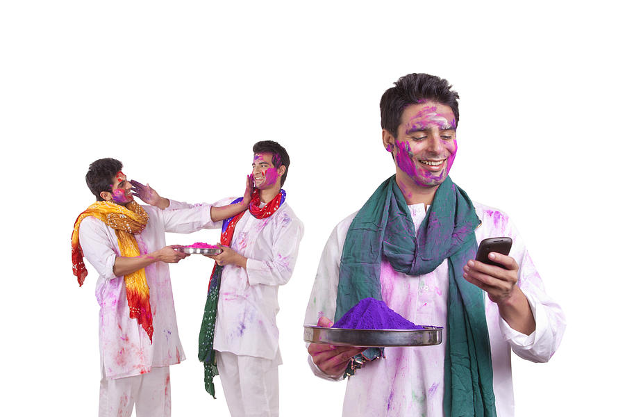 Young man with holi colour reading an sms Photograph by IndiaPix/IndiaPicture
