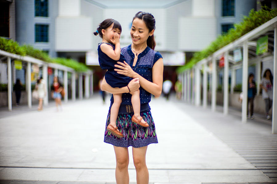 Young mom holding toddler in her arms joyfully. Photograph by images by Tang Ming Tung