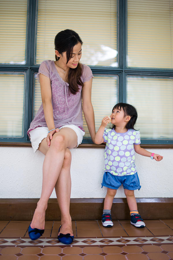 Young mom talking to toddler girl on window sill Photograph by images by Tang Ming Tung