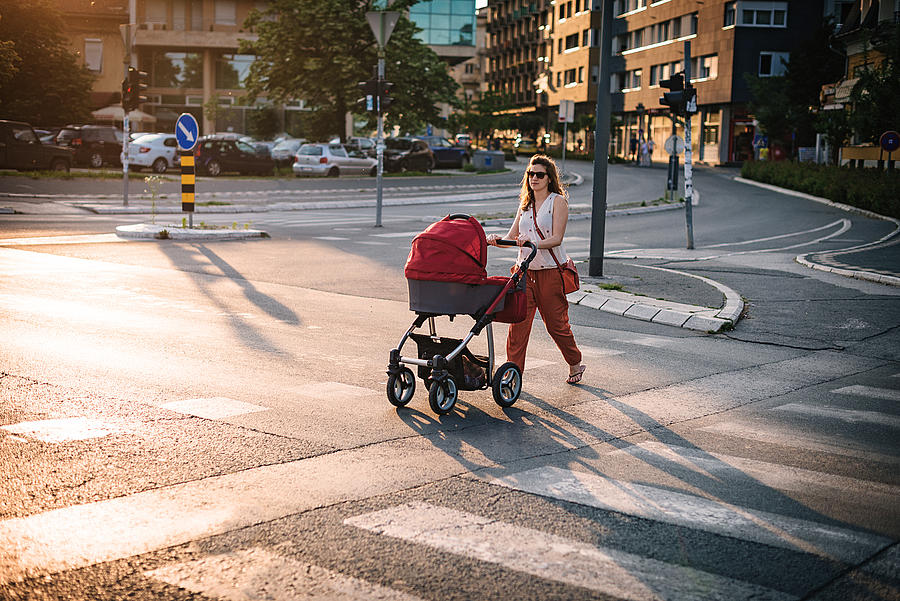 Young mother walking across the pedestrian crosswalk Photograph by Drazen_