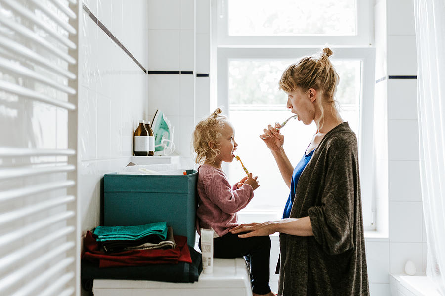 Young mother with a child brushing teeth in the morning Photograph by Visualspace