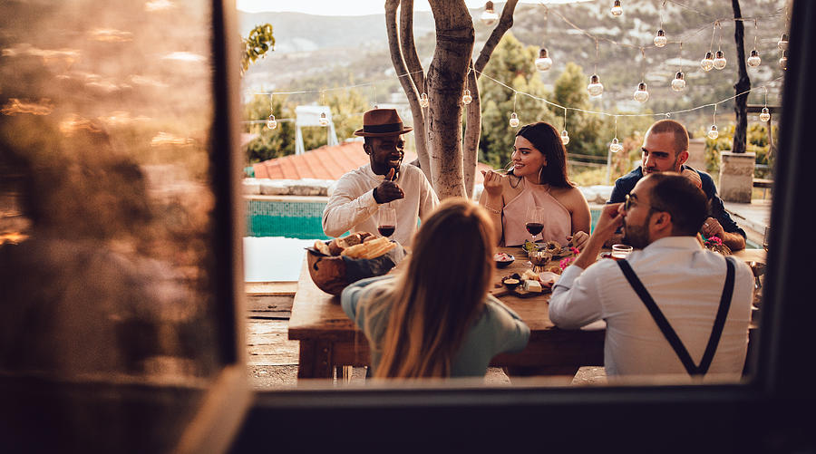 Young multi-ethnic friends and couples having lunch at village house Photograph by Wundervisuals