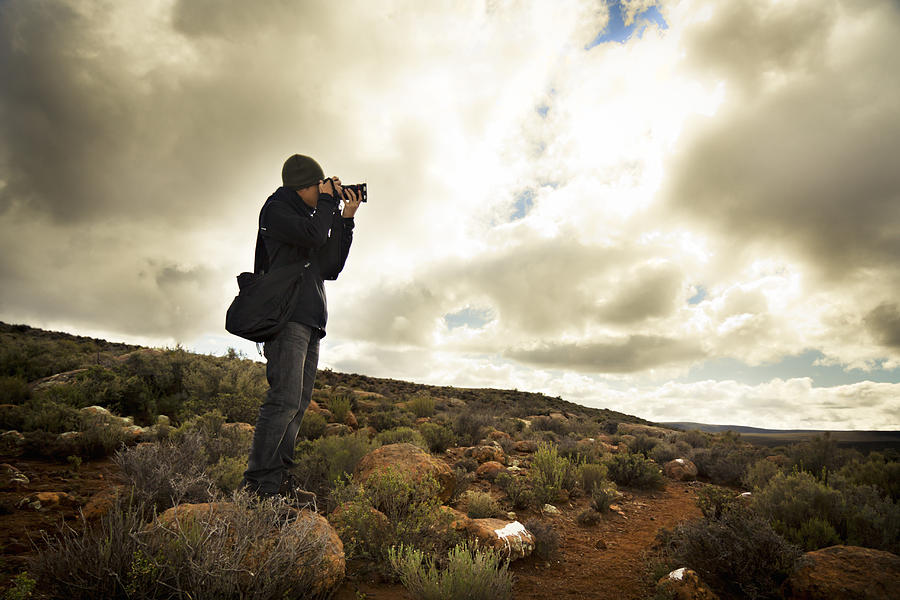 Young photographer aiming his camera to take a shot with beautiful nature scenery and dramatic sky in the background, Sutherland, Great Karoo, Groot Karoo, Northern Cape Province, South Africa Photograph by Ananda van der Merwe