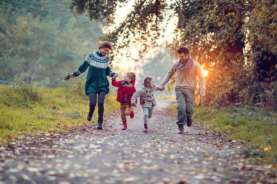 Young playful family having fun while running in the park. Photograph by BraunS