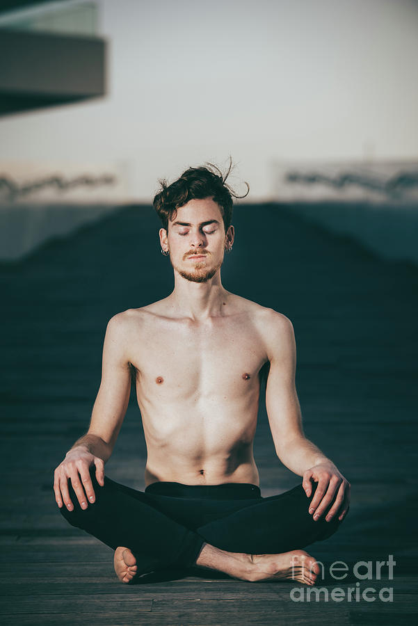 Young red-haired man practicing the lotus yoga posture, Padmasan Photograph by Joaquin Corbalan