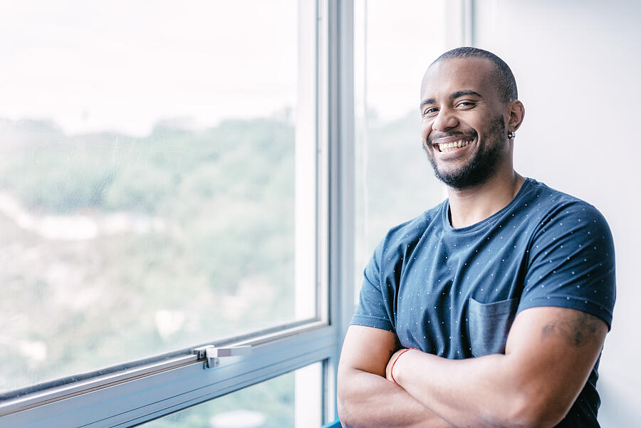 Young Smiling Brazilian Businessman At Window In Office Photograph by Golero