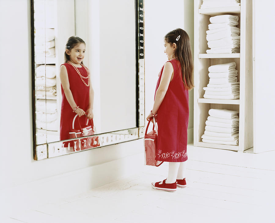 Young, Smiling Girl Looking at Her Reflection in the Mirror Photograph by Lottie Davies