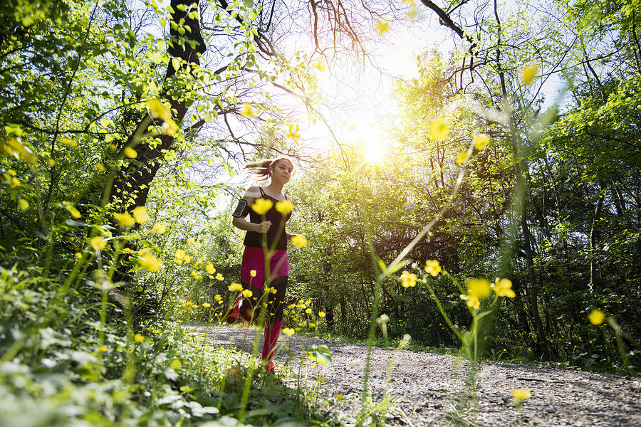 Young sporty woman jogging through the forest. Photograph by ArtistGNDphotography