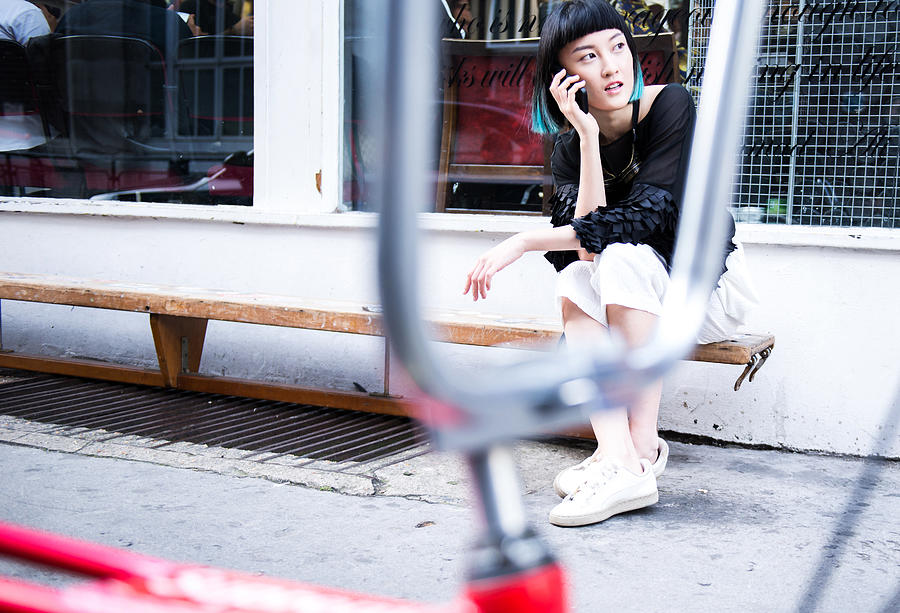 Young stylish woman sitting outside shop making smartphone call Photograph by Bonfanti Diego