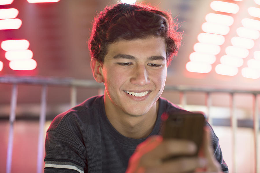 Young teenage boy texting at a fair at night Photograph by Eternity in an Instant
