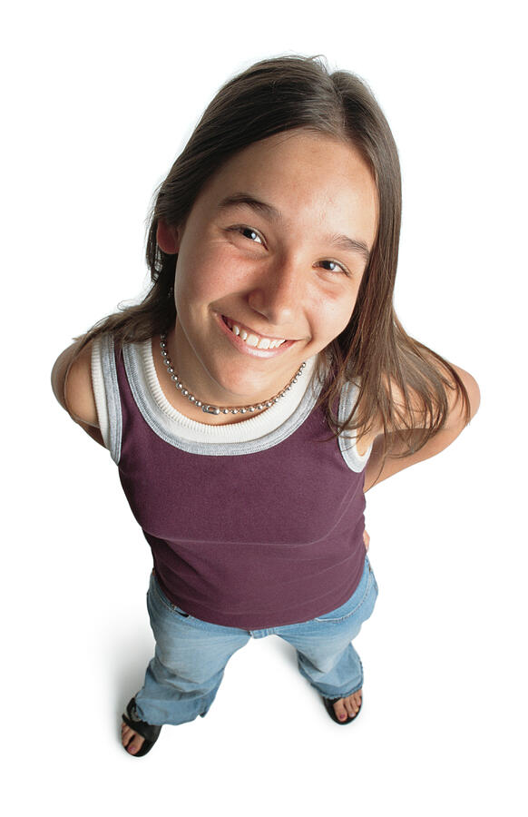 Young Teenage Caucasian Girl Wearing A Purple Tanktop And Blue Jeans Smiles While Looking Up Into The Camera Photograph by Photodisc