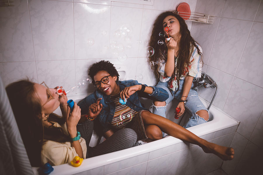 Young teenage girls being silly and having fun blowing bubbles Photograph by Wundervisuals