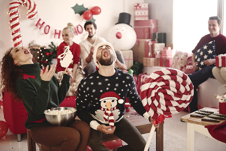 Young woman and man catching popcorn in open mouths at christmas party Photograph by Gpointstudio