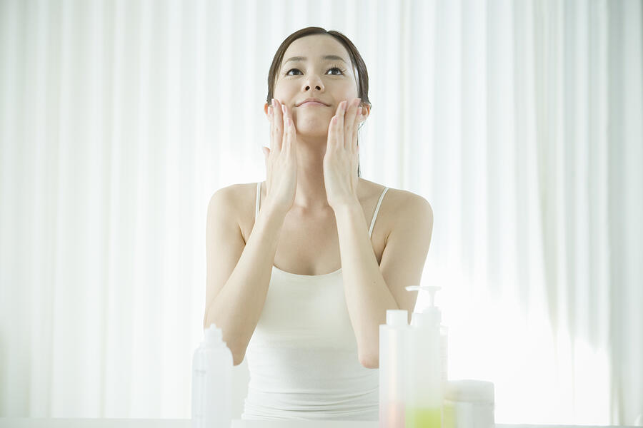 Young woman applying facial cream Photograph by Indeed