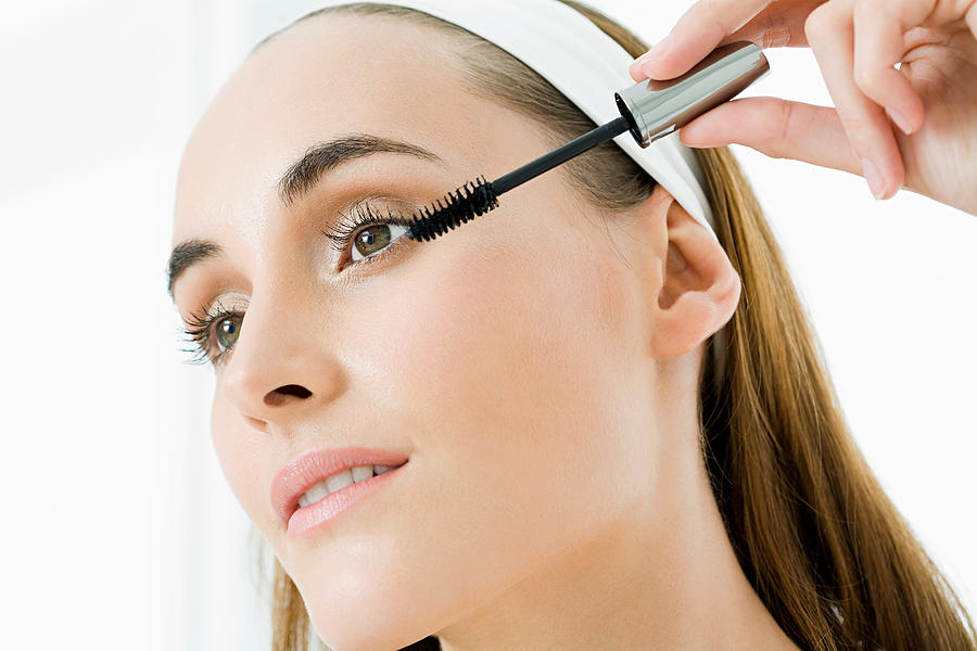 Young woman applying mascara Photograph by Image Source