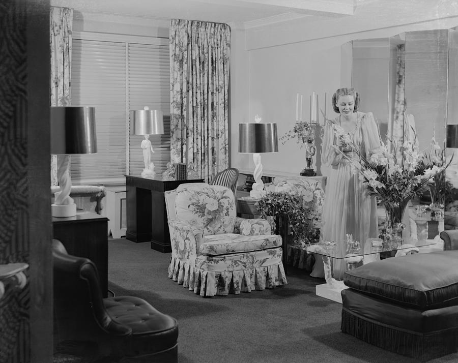 Young woman arranging flowers in living room Photograph by George Marks