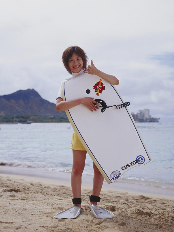 Young woman at a beach, holding paddleboard Photograph by Dex Image
