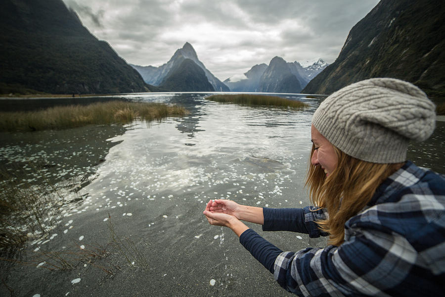 Young woman catches fresh water from lake Photograph by Swissmediavision