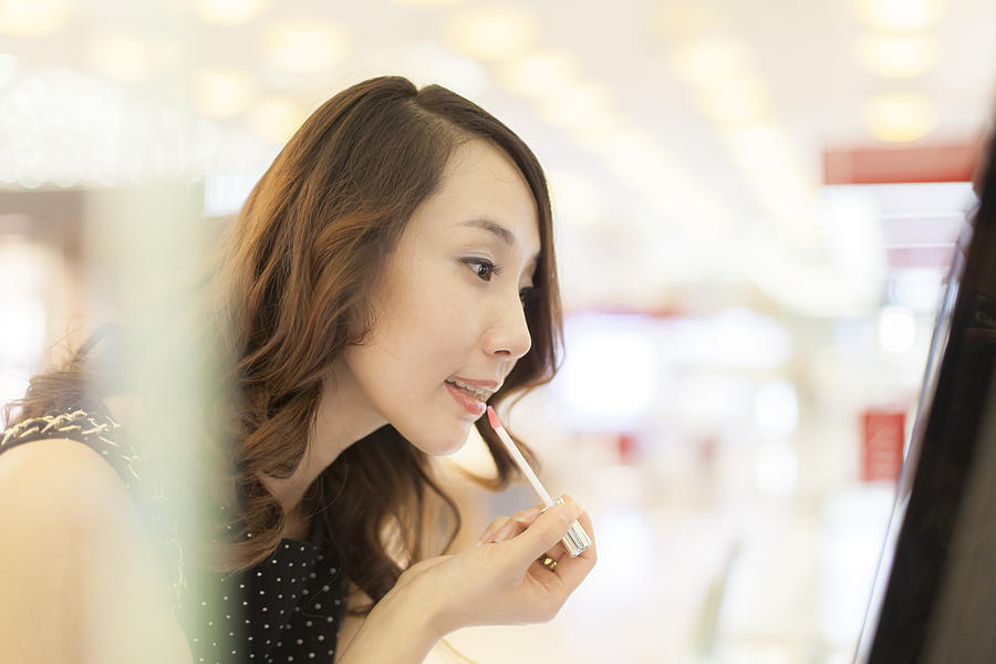 Young Woman Choosing Cosmetics In Shopping Mall Photograph by Czqs2000 / Sts