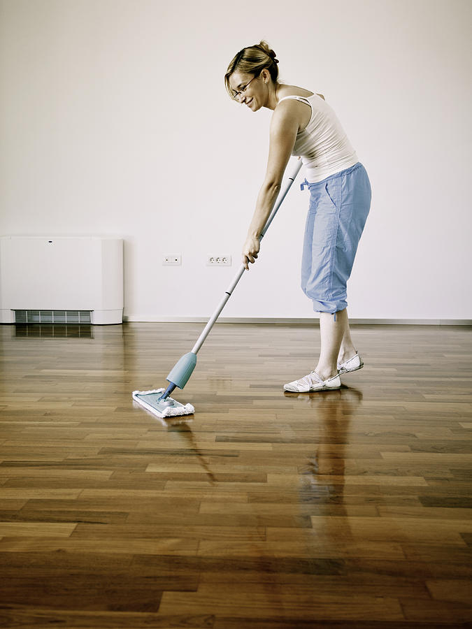 Young woman cleaning wooden floor Photograph by Vm