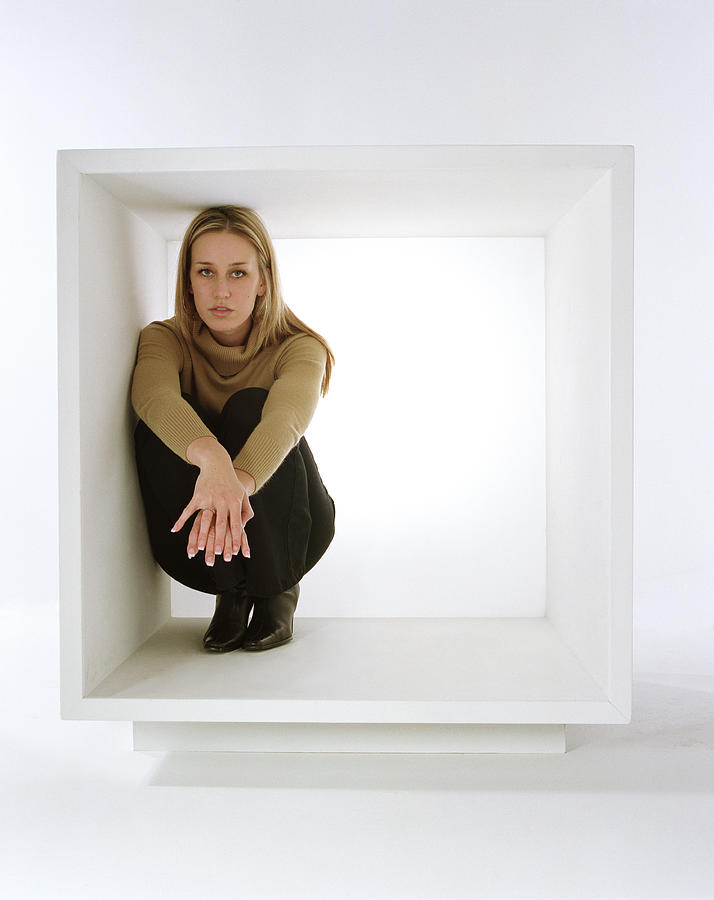 Young woman crouching inside white box Photograph by Kirk Weddle