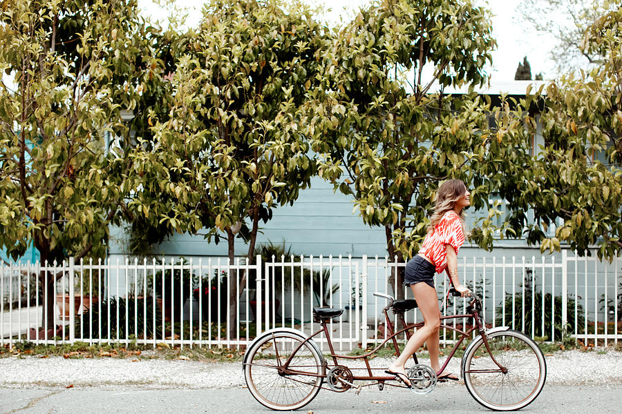 Young woman cycling alone on tandem bicycle along street Photograph by Sasha Gulish