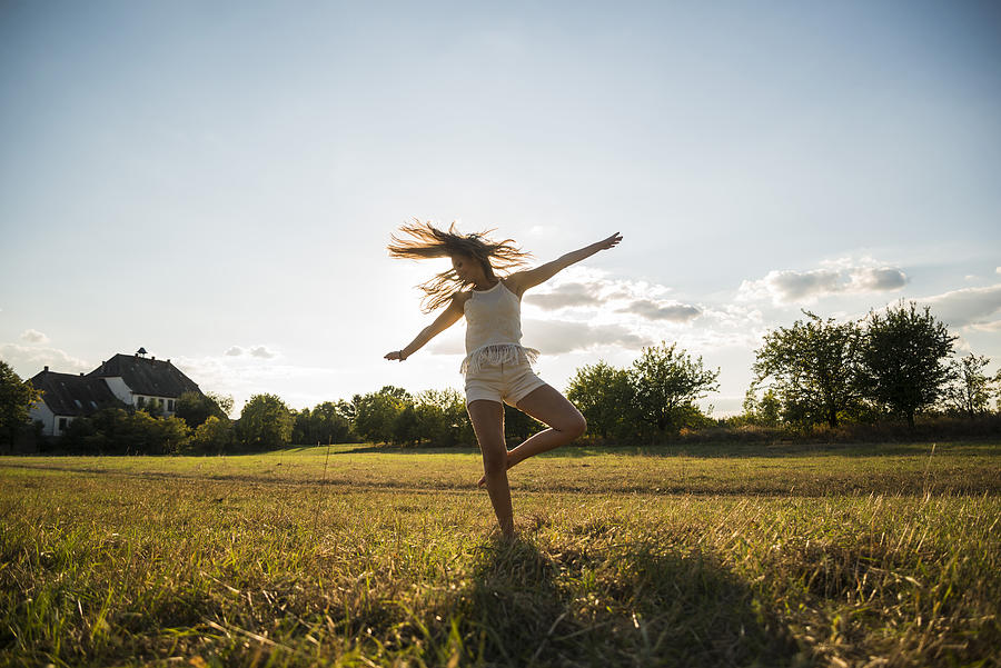 Young woman dancing on a meadow at backlight Photograph by Westend61