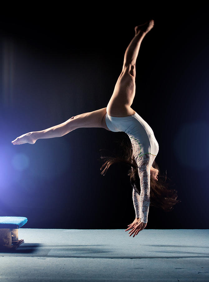 Young woman doing gymnastics jump Photograph by Sanjeri