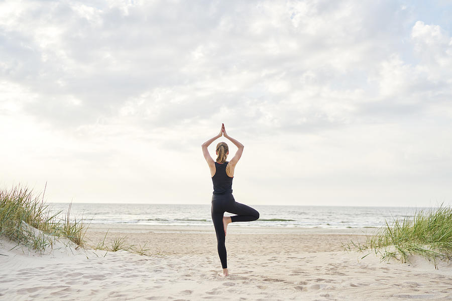 Young woman doing yoga on the beach Photograph by Zhimsa Lawrence
