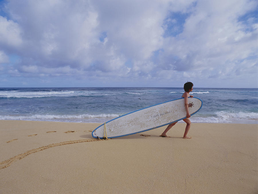 Young woman dragging surfboard on beach Photograph by Dex Image