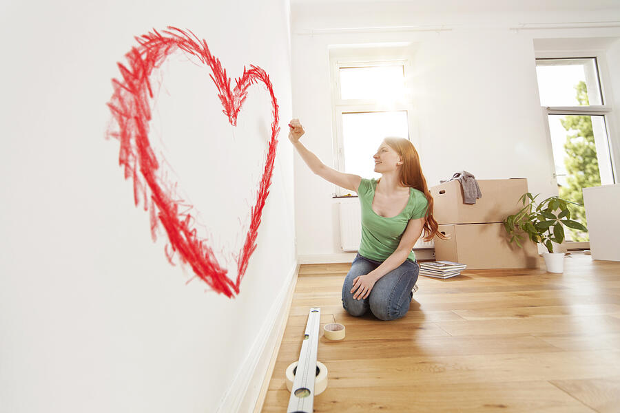 Young woman drawing a heart on a wall in new apartment Photograph by Westend61