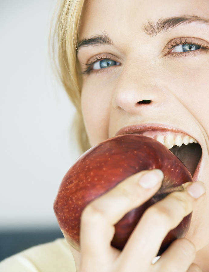 Young woman eating apple, portrait, close-up Photograph by Dan Dalton