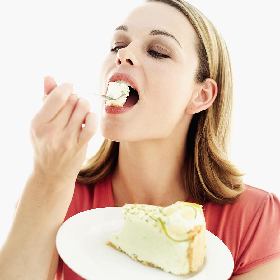 Young woman eating cheesecake with a fork Photograph by Stockbyte