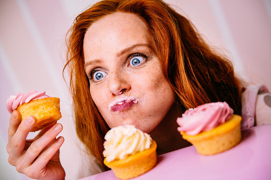 Young Woman Eating Cupcakes With A Lot Of Enthusiasm Photograph by Wundervisuals