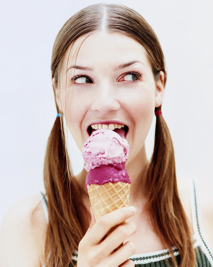 Young woman eating ice-cream, close-up, portrait Photograph by Roger Wright