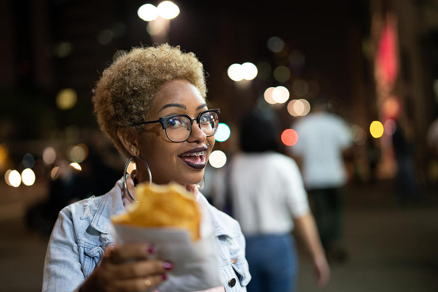 Young Woman Eating Pastel on the Street After Work Photograph by FG Trade