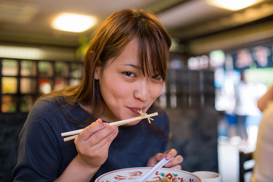 Young woman eating ramen noodle in old Japanese restaurant Photograph by Satoshi-K