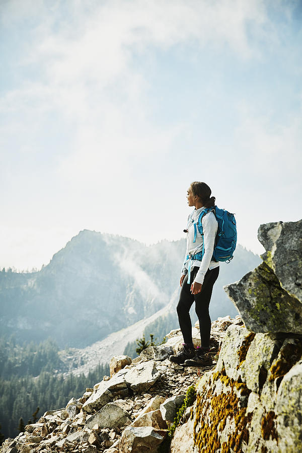 Young woman enjoying view from outlook during hike in mountains Photograph by Thomas Barwick