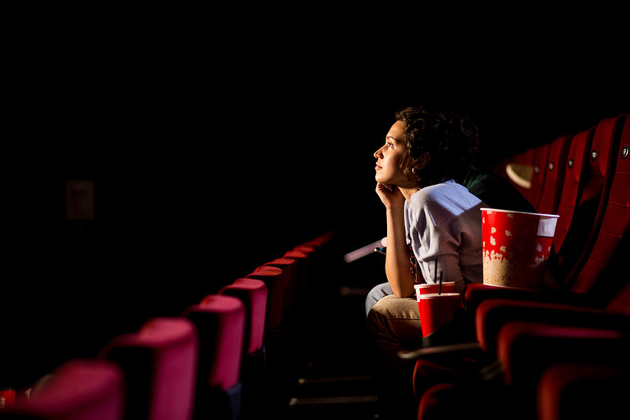 Young woman enjoying watching movie at the cinema Photograph by MixMedia