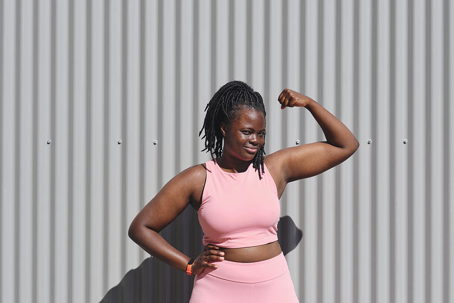 Young woman flexing biceps on sunny day Photograph by Westend61