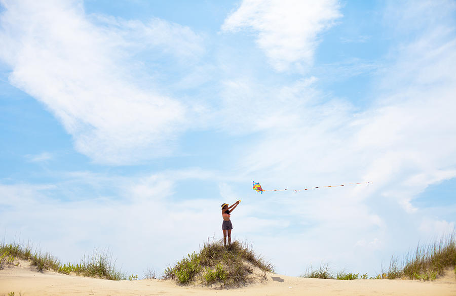 Young woman flying kite on summery day at the beach Photograph by Epicurean