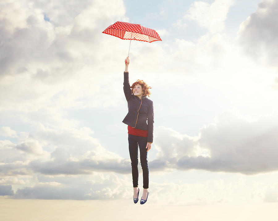 Young woman flying with umbrella. Photograph by Tim Robberts