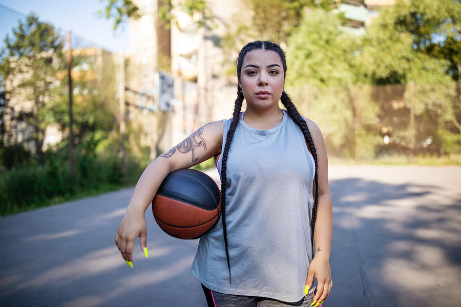 Young woman holding basketball on court Photograph by Luis Alvarez