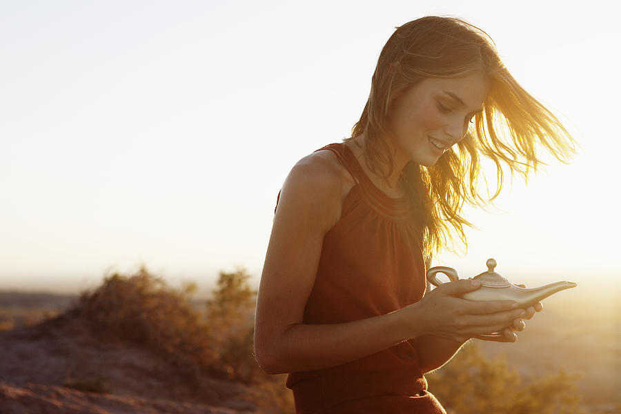 Young woman holding genie lamp Photograph by Fotosearch Young woman holding genie lamp Photograph by Fotosearch