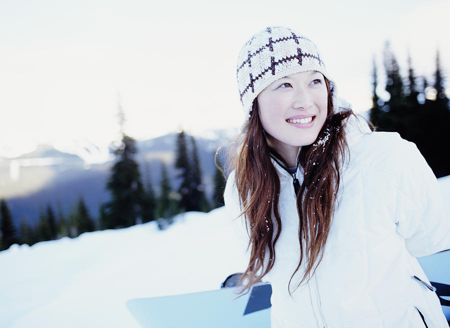 Young woman holding snowboard, smiling Photograph by Digital Vision