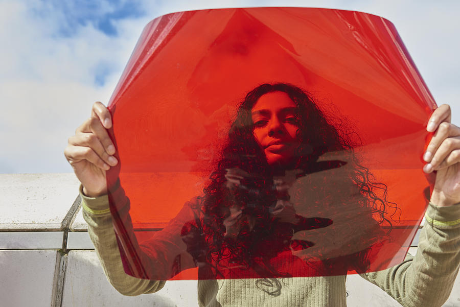 Young woman holding up red filter in front of face Photograph by We Are