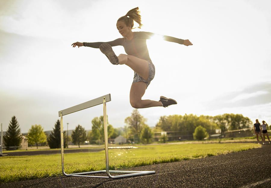 Young woman hurdler on school track Photograph by Tony Anderson