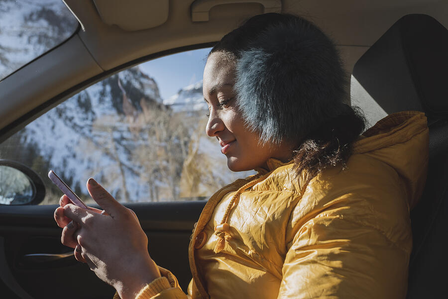 Young woman in car with phone in winter Photograph by Tony Anderson
