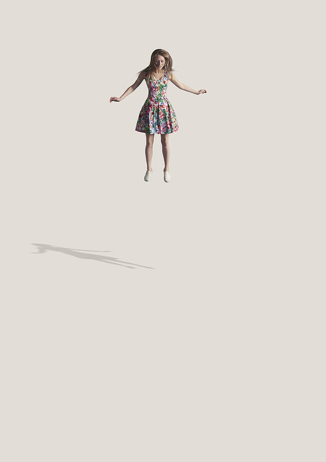 Young woman in flowery dress, jumping in the air Photograph by Klaus Vedfelt