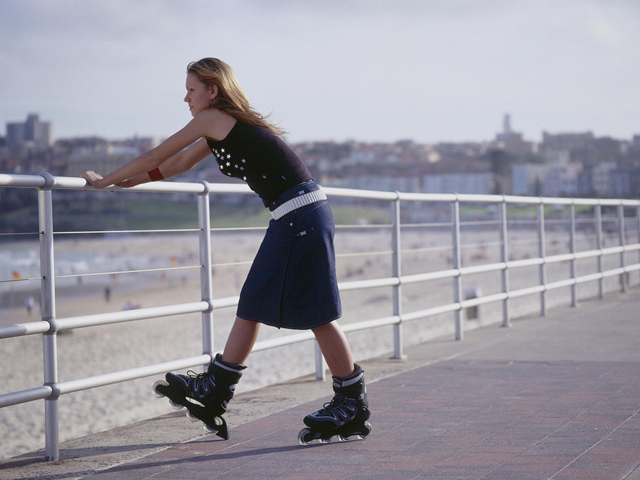 Young woman in inline skate leaning on railing Photograph by Dex Image